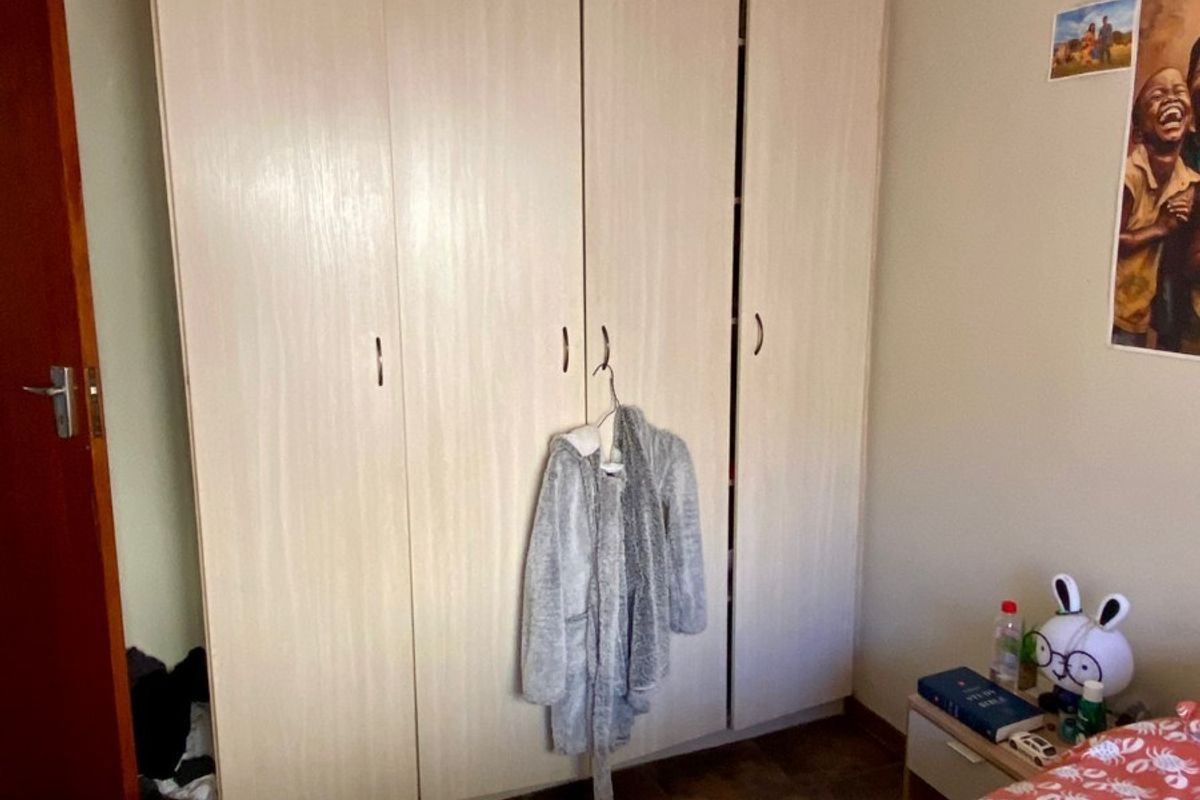 A bedroom featuring built-in floor-to-ceiling wardrobes with light wood-grain finish and crown molding.