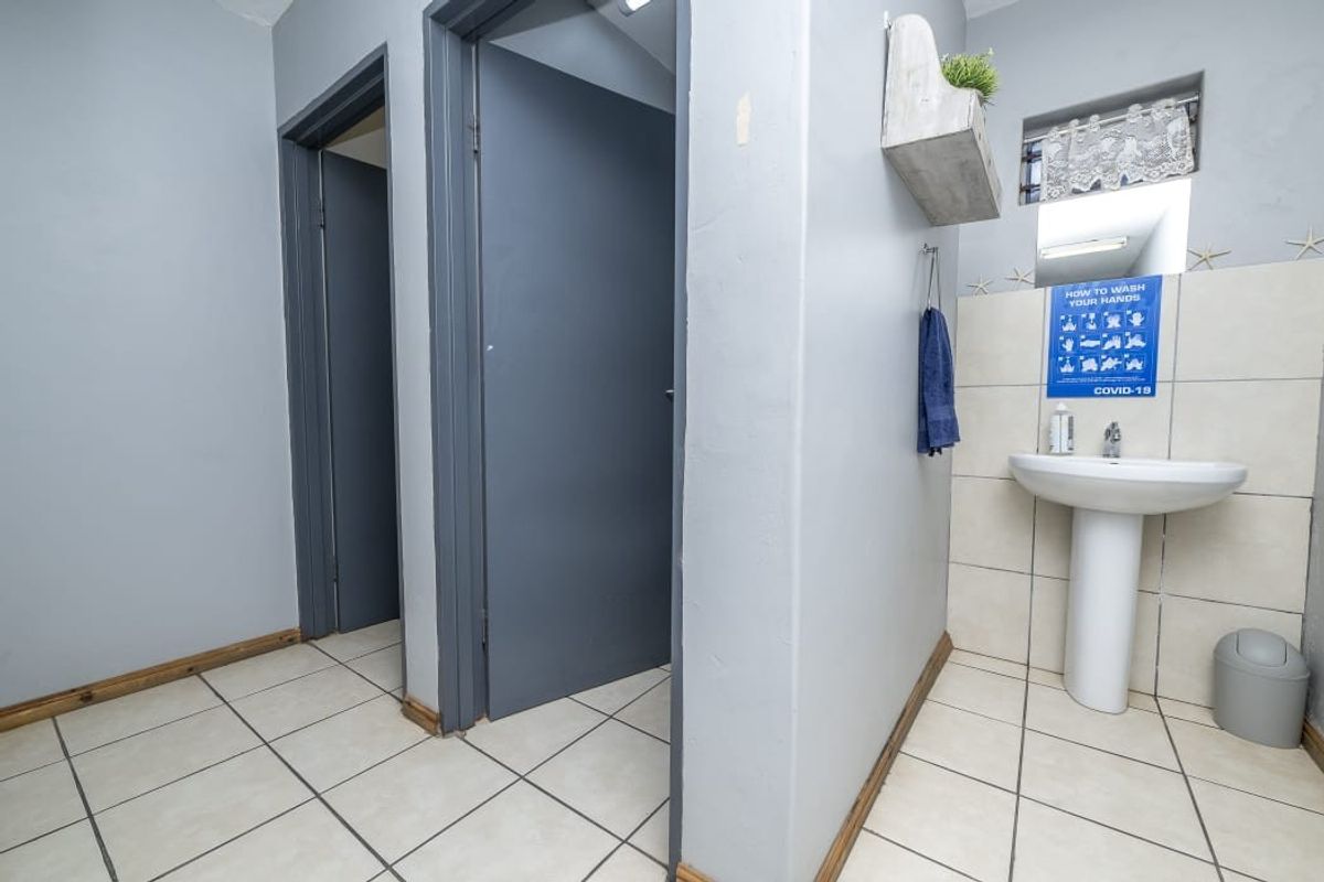 A functional bathroom area featuring a pedestal washbasin, tiled flooring, and neutral wall finishes, providing a clean and practical space.