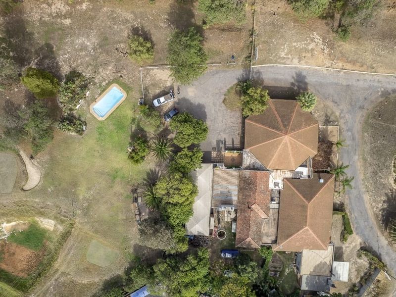 Aerial view of the farm property featuring a swimming pool, multiple roof structures, and extensive surrounding grounds with driveway access.