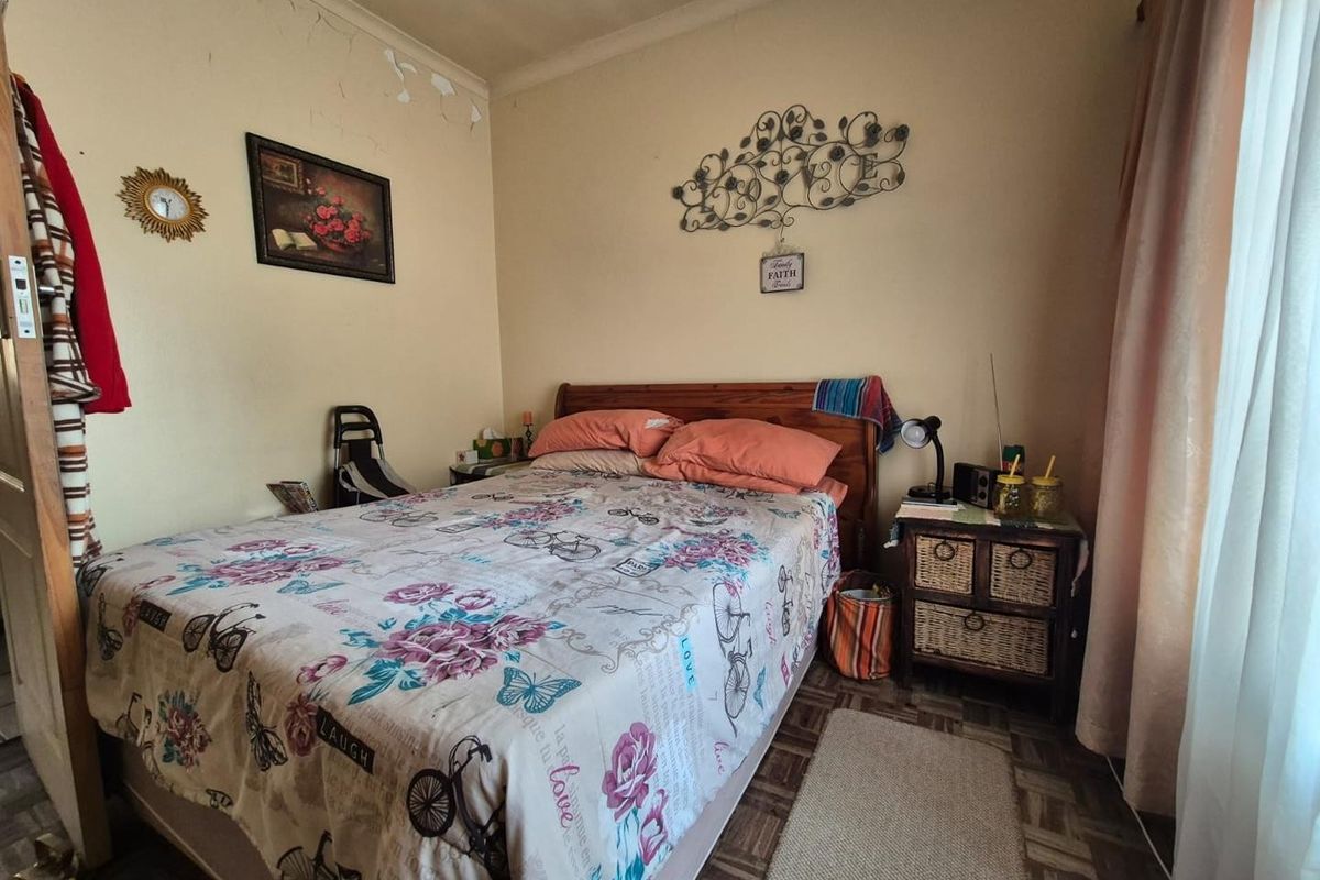 A compact bedroom featuring patterned floor tiles and neutral wall finishes, requiring some cosmetic updates to the ceiling and wall surfaces.
