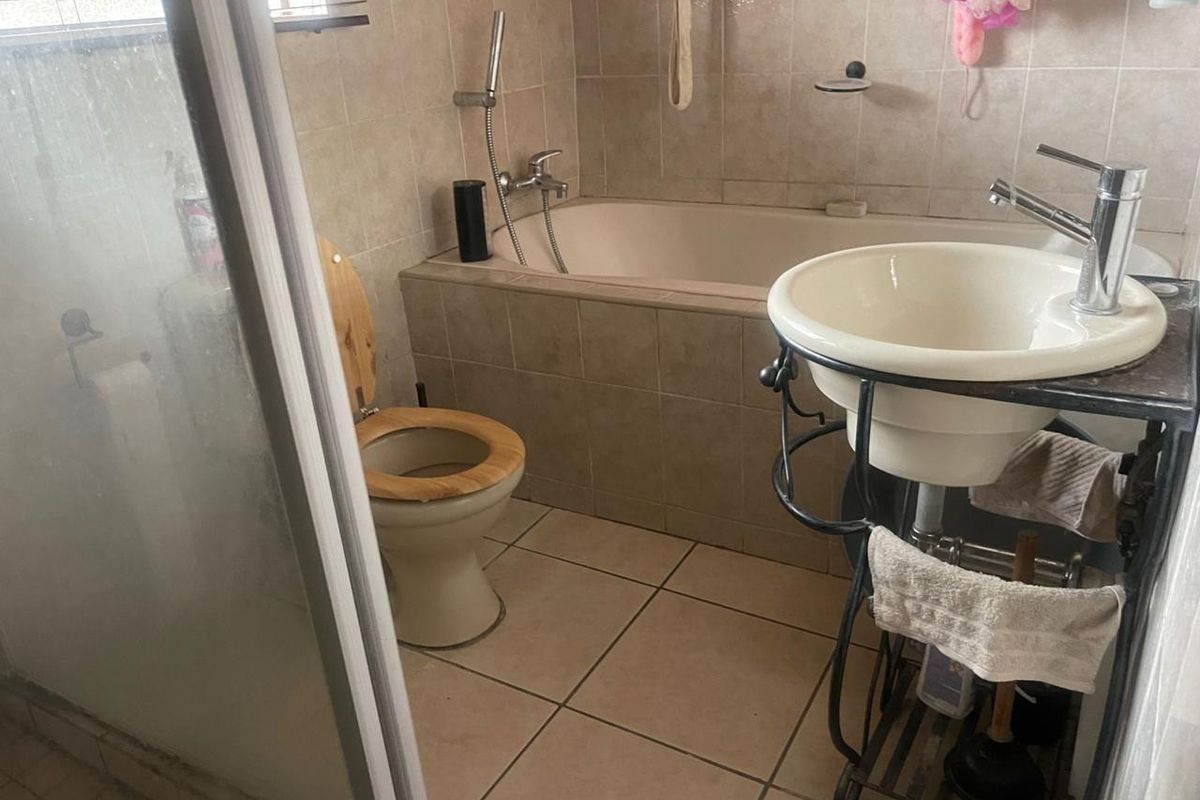 A functional bathroom featuring a built-in bathtub, a shower enclosure, a toilet, and a pedestal-style basin with tiled walls and flooring.
