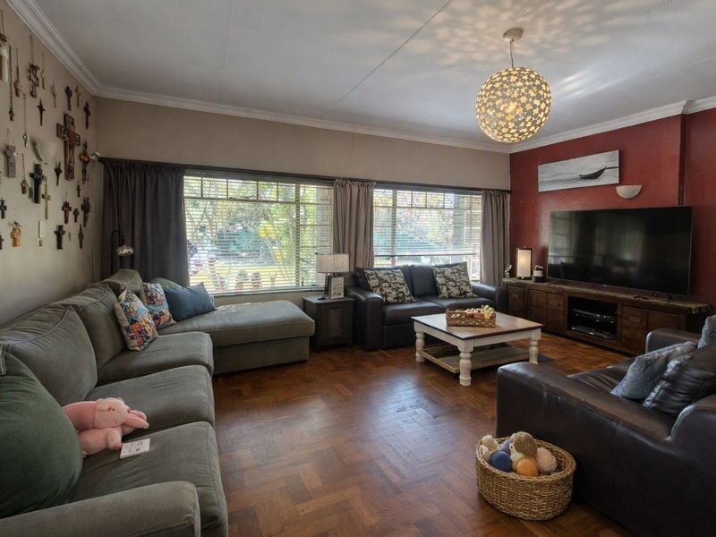 Spacious living room featuring classic parquet flooring, large windows for natural light, and decorative cornicing.
