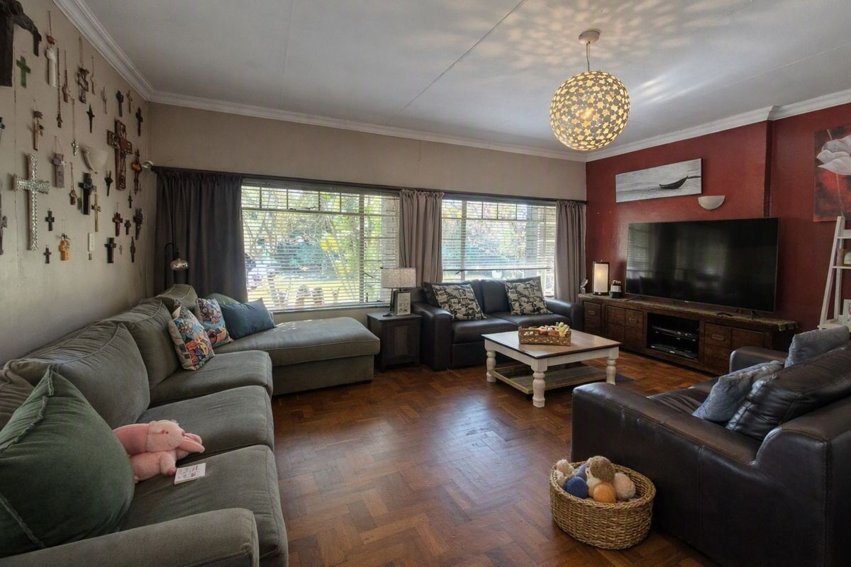 Spacious living room featuring classic parquet flooring, large windows for natural light, and decorative cornicing.