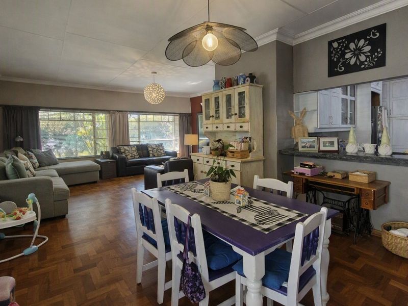 Spacious open-plan living and dining area featuring classic parquet flooring, a convenient pass-through window to the kitchen, and decorative ceiling cornices.