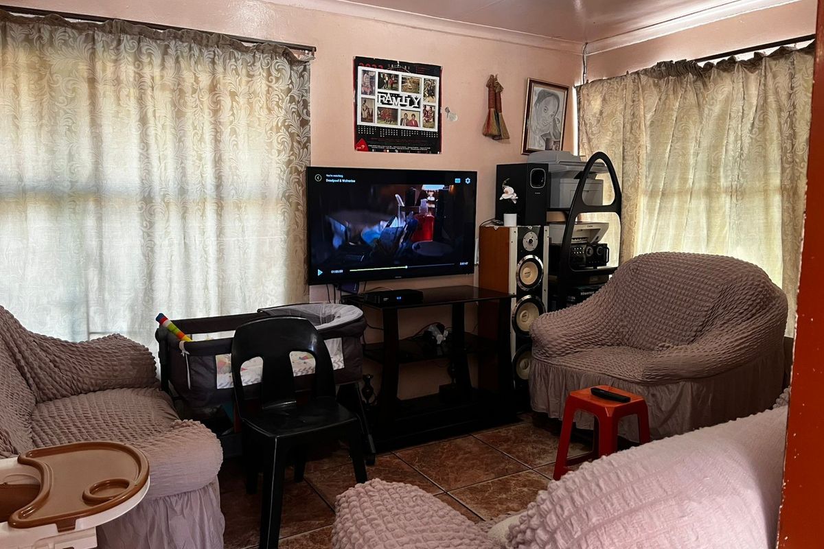 A living room featuring tiled flooring and dual windows, currently used as a multi-purpose family space.