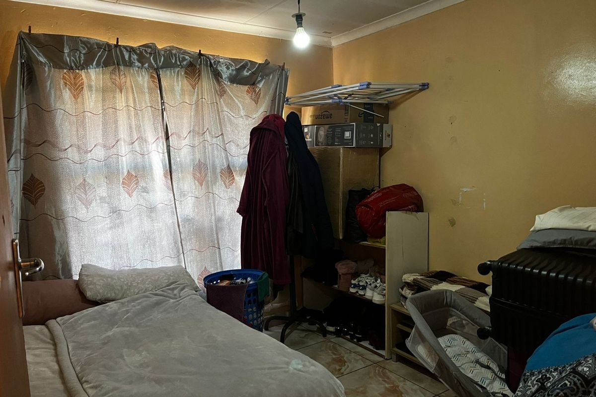 A bedroom featuring tiled flooring and ceiling cornice, currently showing signs of wear including ceiling water staining and wall surface damage.