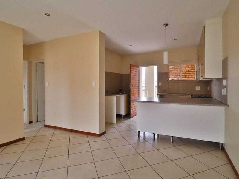 An open-plan living and kitchen area featuring tiled flooring, a breakfast bar, and built-in cabinetry, offering a functional and versatile space.