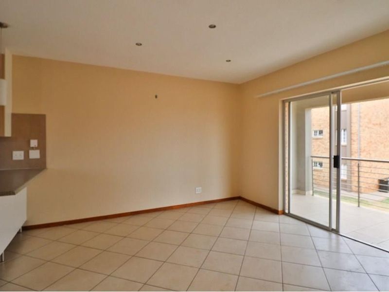 An open-plan living area featuring tiled flooring, recessed lighting, and a sliding glass door leading to a balcony.