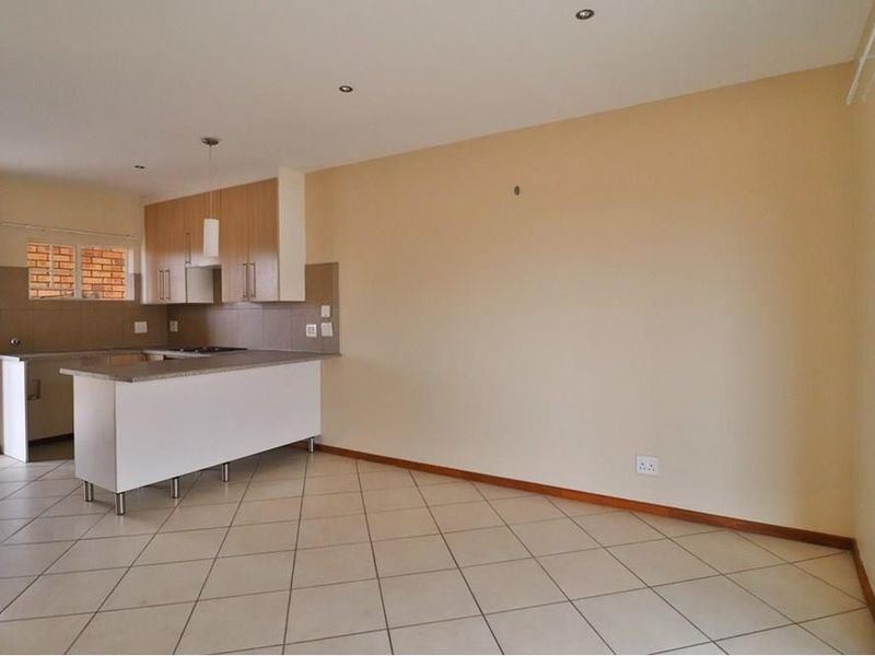 Open-plan living area featuring a functional kitchen with built-in cabinetry, granite countertops, and tiled flooring throughout.