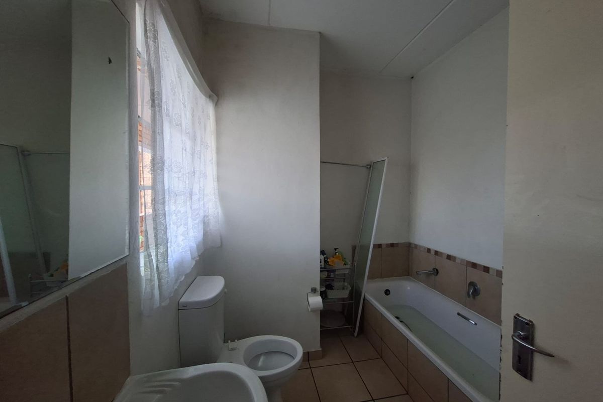 A functional bathroom featuring a standard bathtub, toilet, and vanity basin with tiled flooring and wall accents.