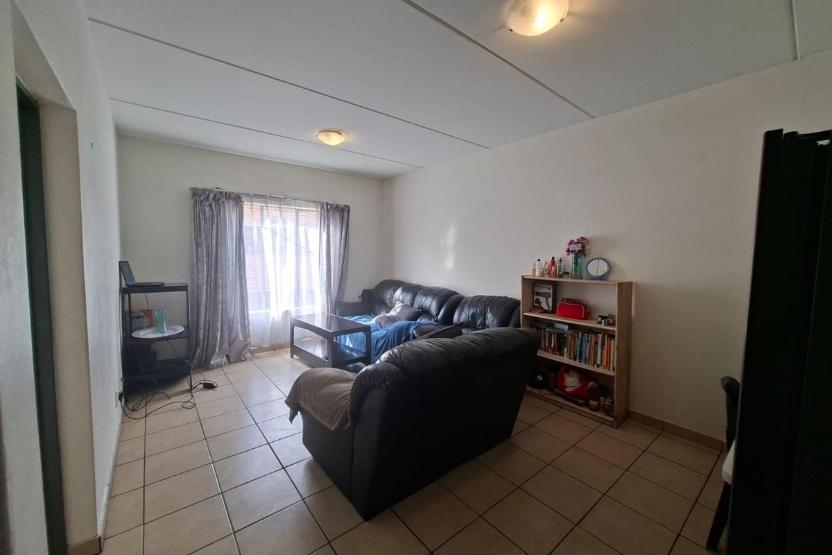 A functional living room featuring tiled flooring and standard ceiling lighting, providing a neutral space for relaxation.