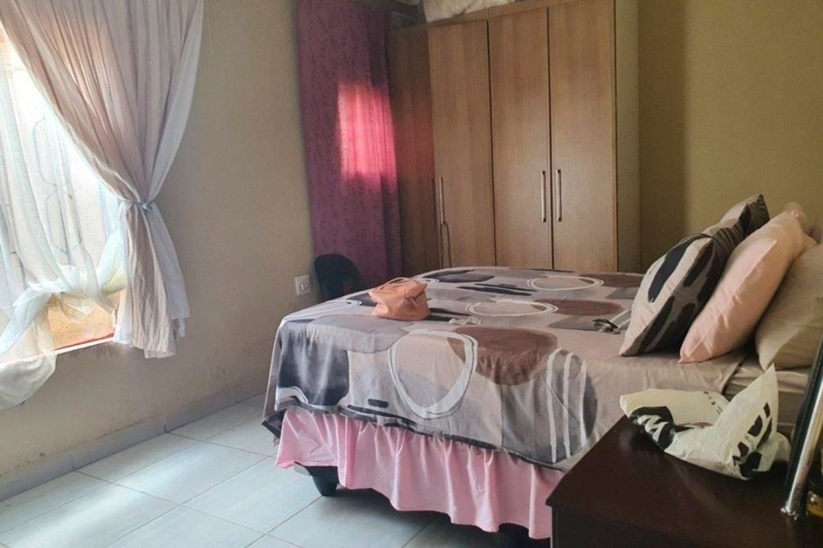 A functional bedroom featuring tiled flooring and a built-in wardrobe, offering a practical layout with natural light from the window.