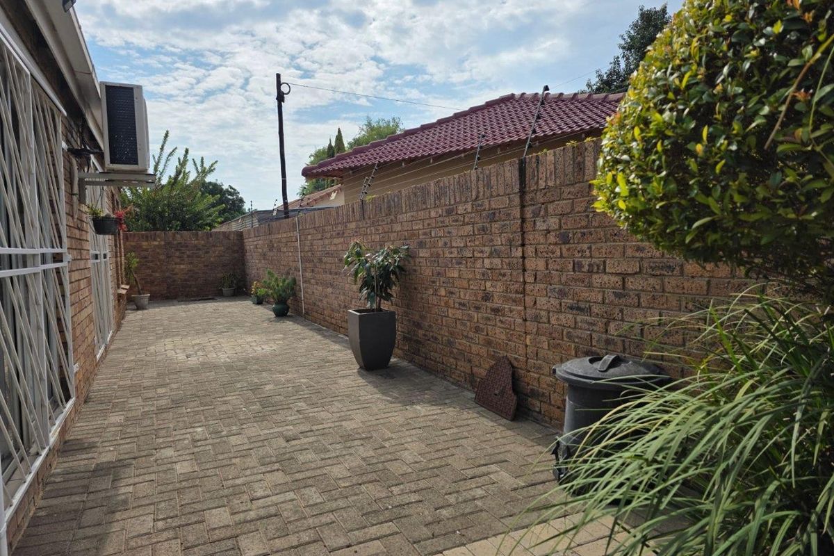 A paved rear courtyard area featuring perimeter brick boundary walls and an external air conditioning unit mounted on the side of the townhouse.