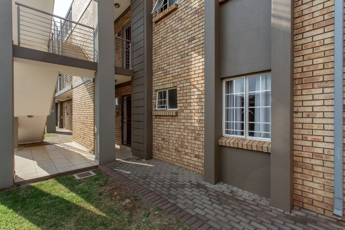 Exterior view of an apartment complex featuring face brick walls, a paved walkway, and an external metal staircase leading to upper levels.