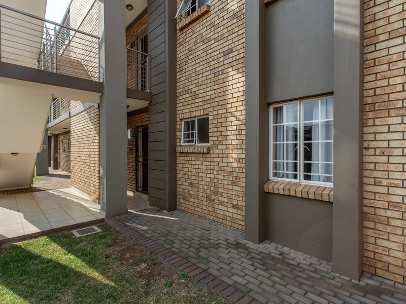 Exterior view of an apartment complex featuring face brick walls, a paved walkway, and an external metal staircase leading to upper levels.