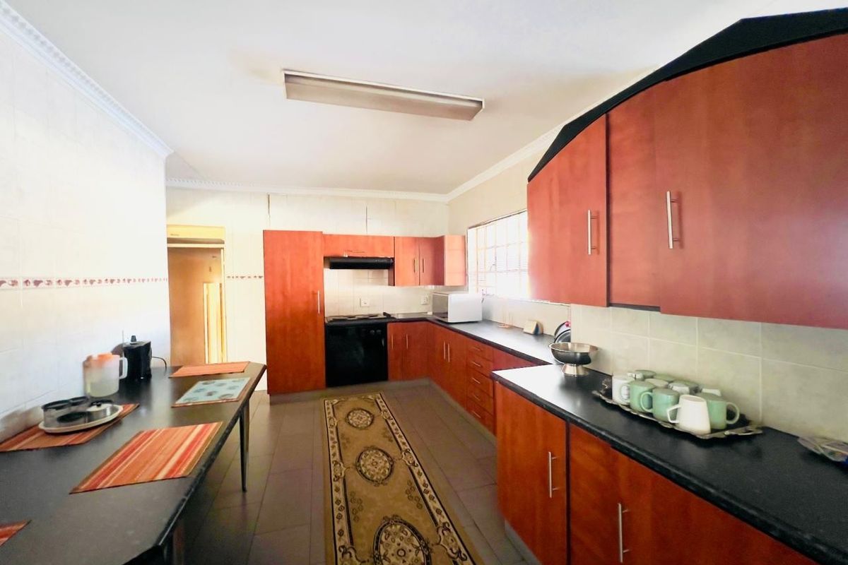 A functional kitchen featuring wooden cabinetry, dark countertops, a built-in oven, and an extractor fan, offering ample storage and workspace.