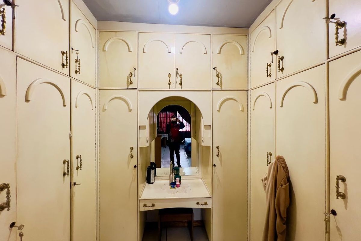 A dressing area featuring extensive built-in cabinetry with integrated vanity, mirror, and overhead storage compartments.