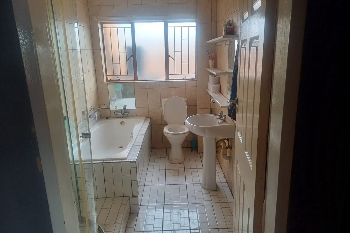 A dated bathroom featuring a built-in bathtub, separate shower enclosure, pedestal sink, and toilet with tiled walls and flooring.