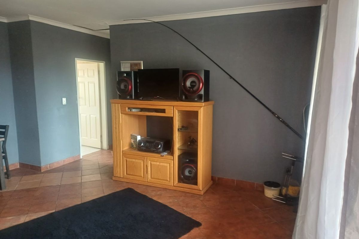 A living room area featuring terracotta floor tiles, dark grey painted walls, and a doorway leading to an adjacent room.