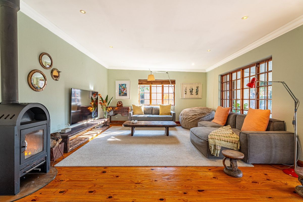 Spacious living room featuring polished timber flooring, a built-in wood-burning fireplace, recessed downlighting, and large timber-framed windows.