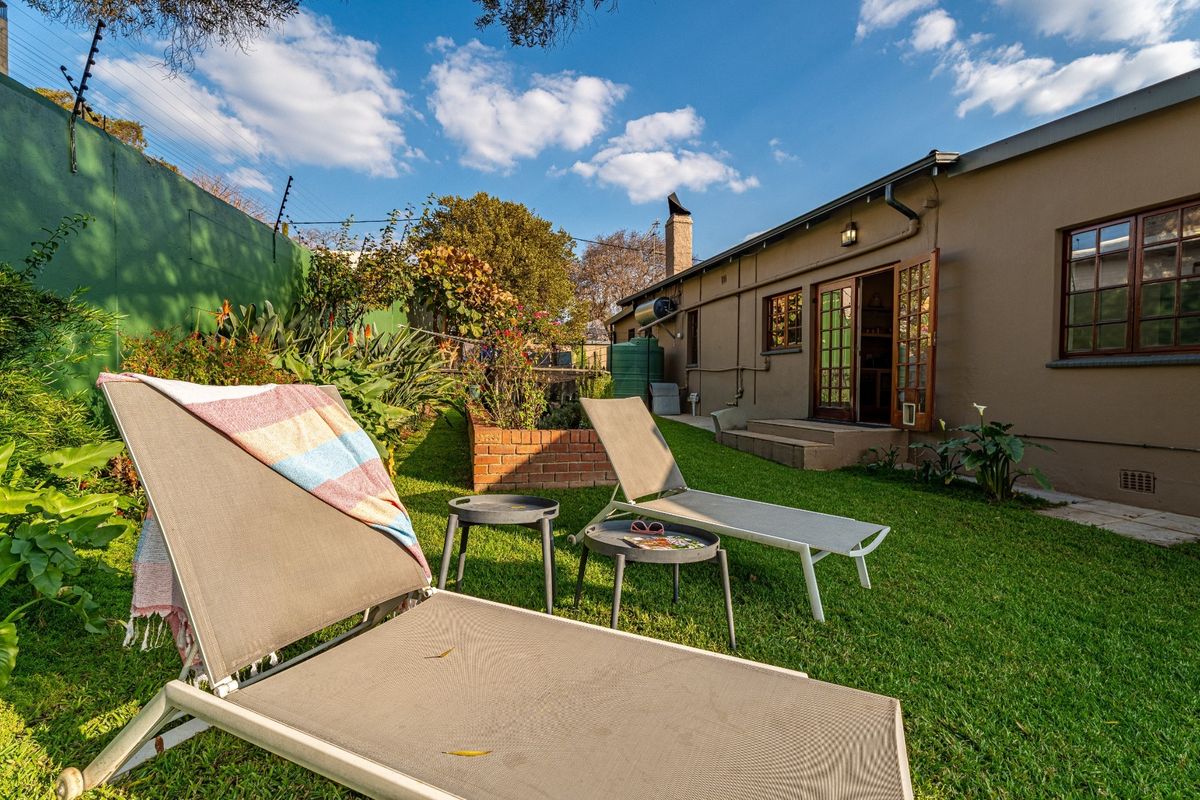 A private rear garden featuring a lawn, brick planter, and direct access to the home via wooden French doors.
