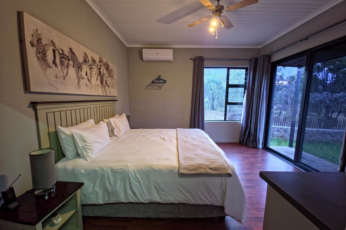 A well-maintained bedroom featuring a ceiling fan, wall-mounted air conditioning unit, and large sliding glass doors providing access to the outdoor area.