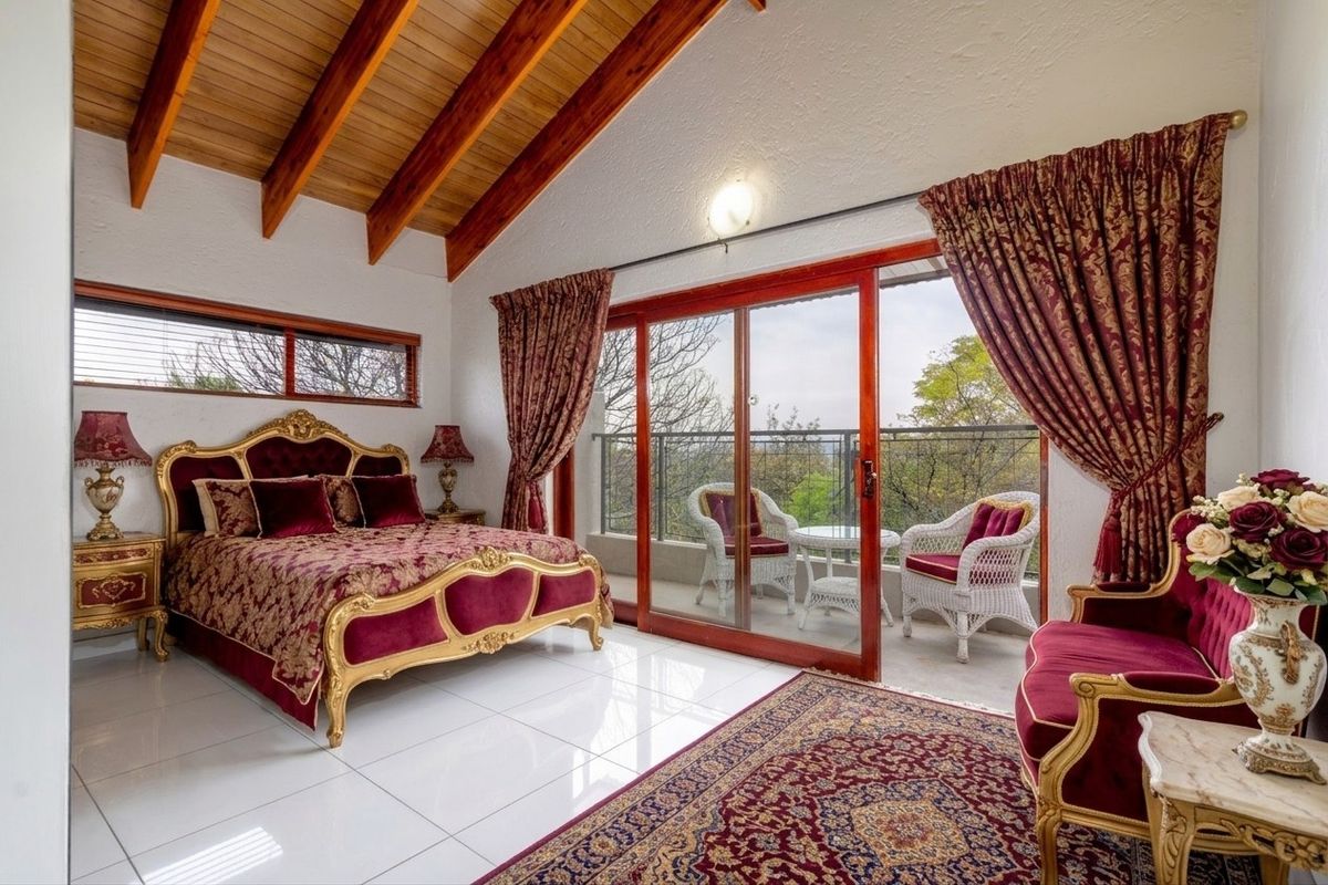 Spacious bedroom featuring high vaulted timber-beamed ceilings, polished tile flooring, and large sliding glass doors opening onto a private balcony with scenic views.