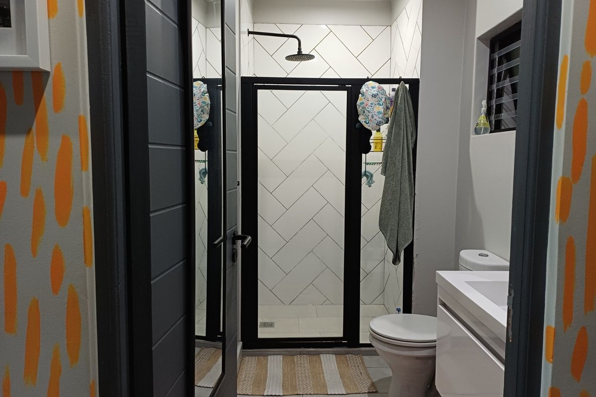 Modern bathroom featuring a walk-in shower with black frame, herringbone wall tiling, vanity basin, and toilet.