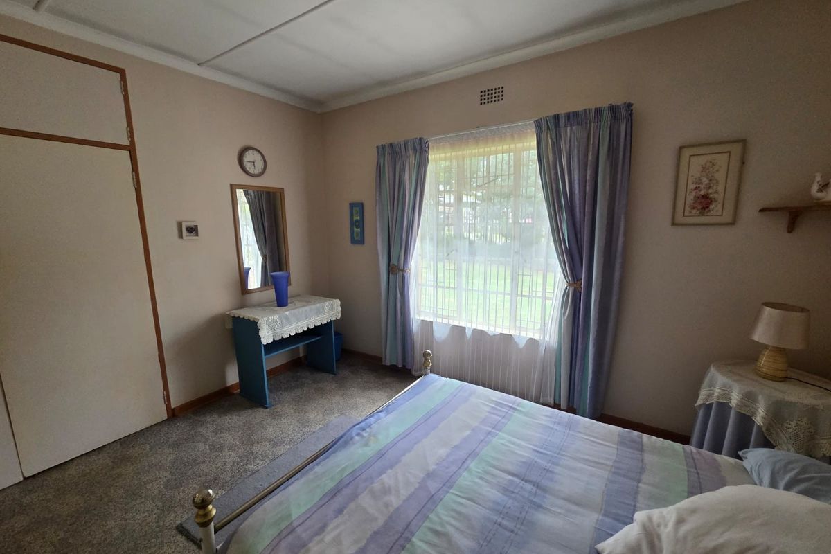 A bedroom featuring built-in cupboards, carpeted flooring, and a window with natural light.