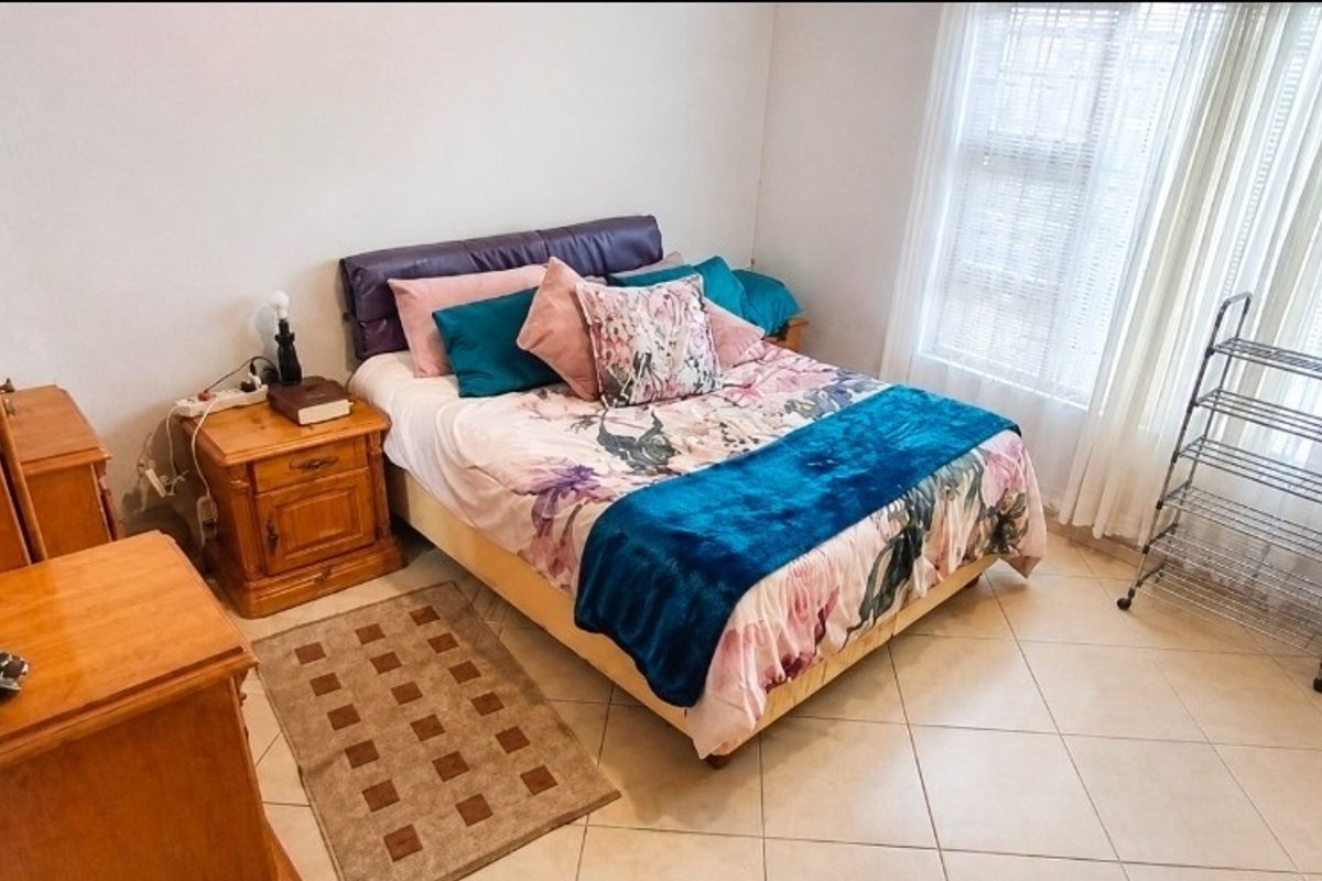 A functional bedroom featuring tiled flooring and natural light through large windows.