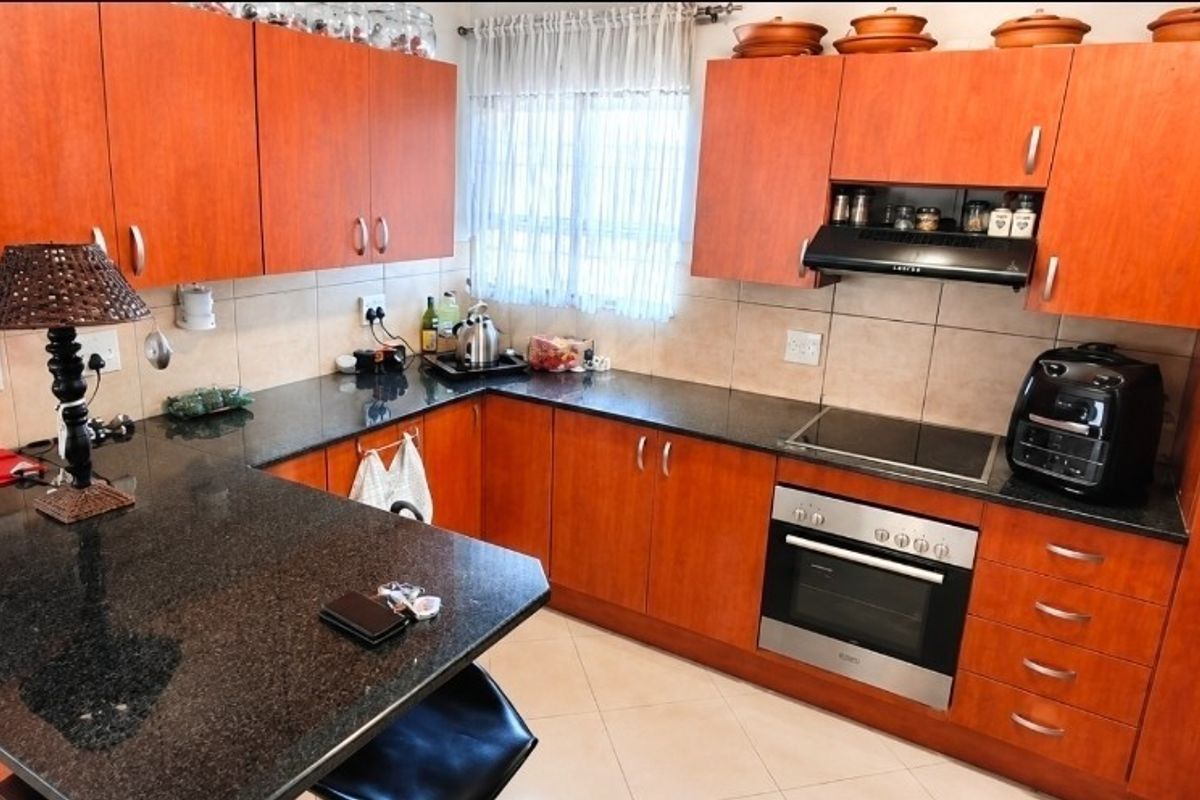 A functional kitchen featuring granite countertops, laminate cabinetry, and built-in cooking appliances, offering a practical layout for daily meal preparation.