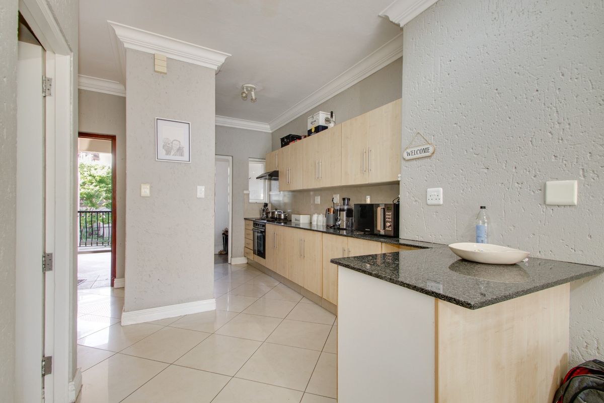 A functional kitchen featuring light wood cabinetry, granite countertops, ceramic floor tiles, and built-in appliances, offering a clean and practical workspace.