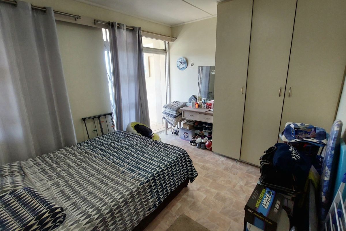 A bedroom featuring built-in wardrobes and direct access to a balcony through sliding glass doors.