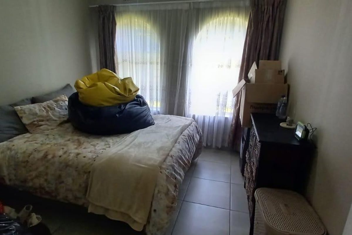 A bedroom featuring tiled flooring and large arched windows with curtains, providing natural light.