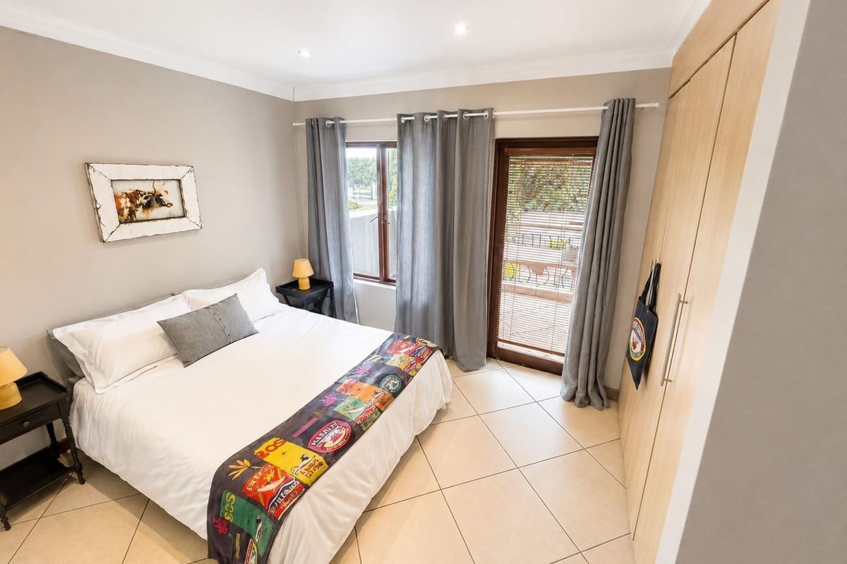 A well-maintained bedroom featuring tiled flooring, built-in wooden wardrobes, and direct access to an outdoor patio area through a glass door.