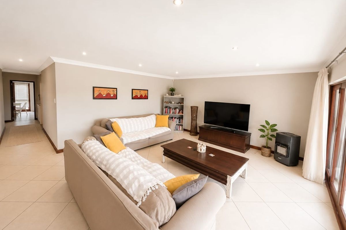 Spacious living room featuring neutral tiled flooring, recessed downlighting, and large glass sliding doors providing access to the exterior.