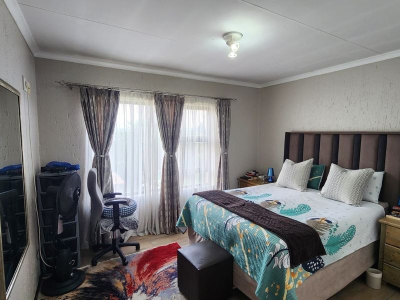 A bedroom featuring textured walls, a large window with curtain tracks, and a central ceiling light fixture.