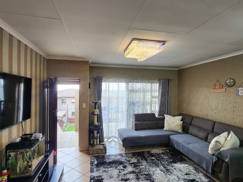 A comfortable living room featuring tiled flooring, a modern crystal ceiling light, and sliding glass doors providing access to an outdoor patio area.