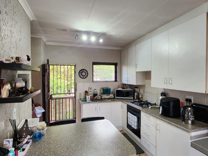 Functional kitchen featuring white cabinetry, granite-look countertops, built-in oven with gas hob, and direct access to an outdoor area.