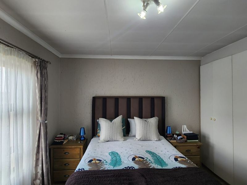 A well-lit bedroom featuring built-in wardrobes and textured wall finishes, providing a functional and comfortable living space.