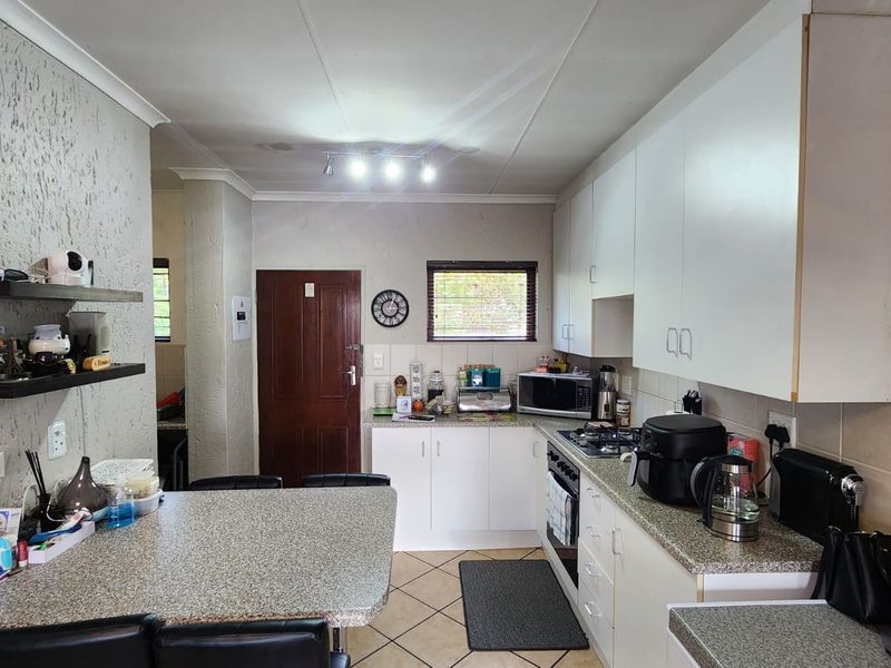 Functional kitchen featuring white cabinetry, granite-style countertops, built-in gas hob, and an integrated breakfast bar area.