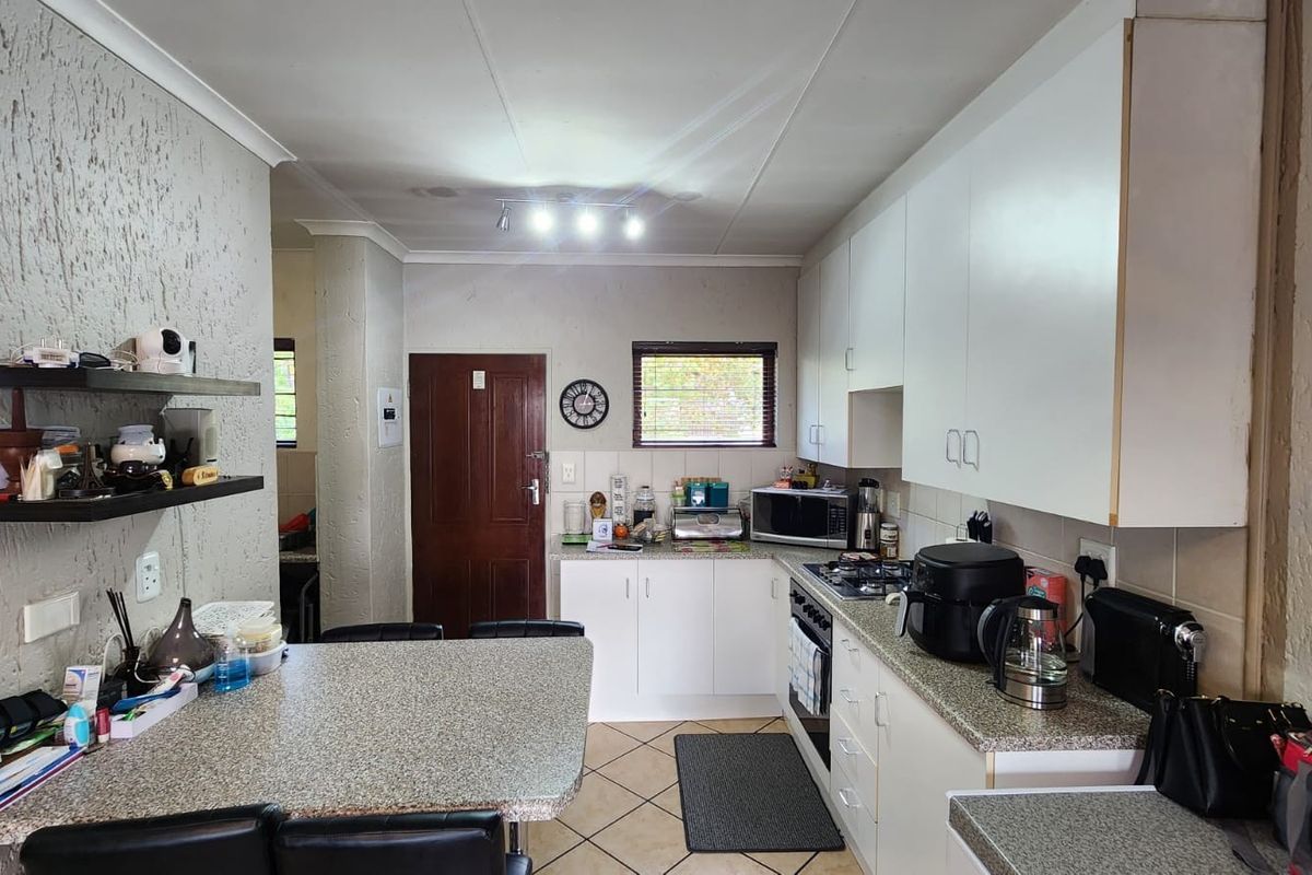 Functional kitchen featuring white cabinetry, granite-style countertops, built-in gas hob, and an integrated breakfast bar area.