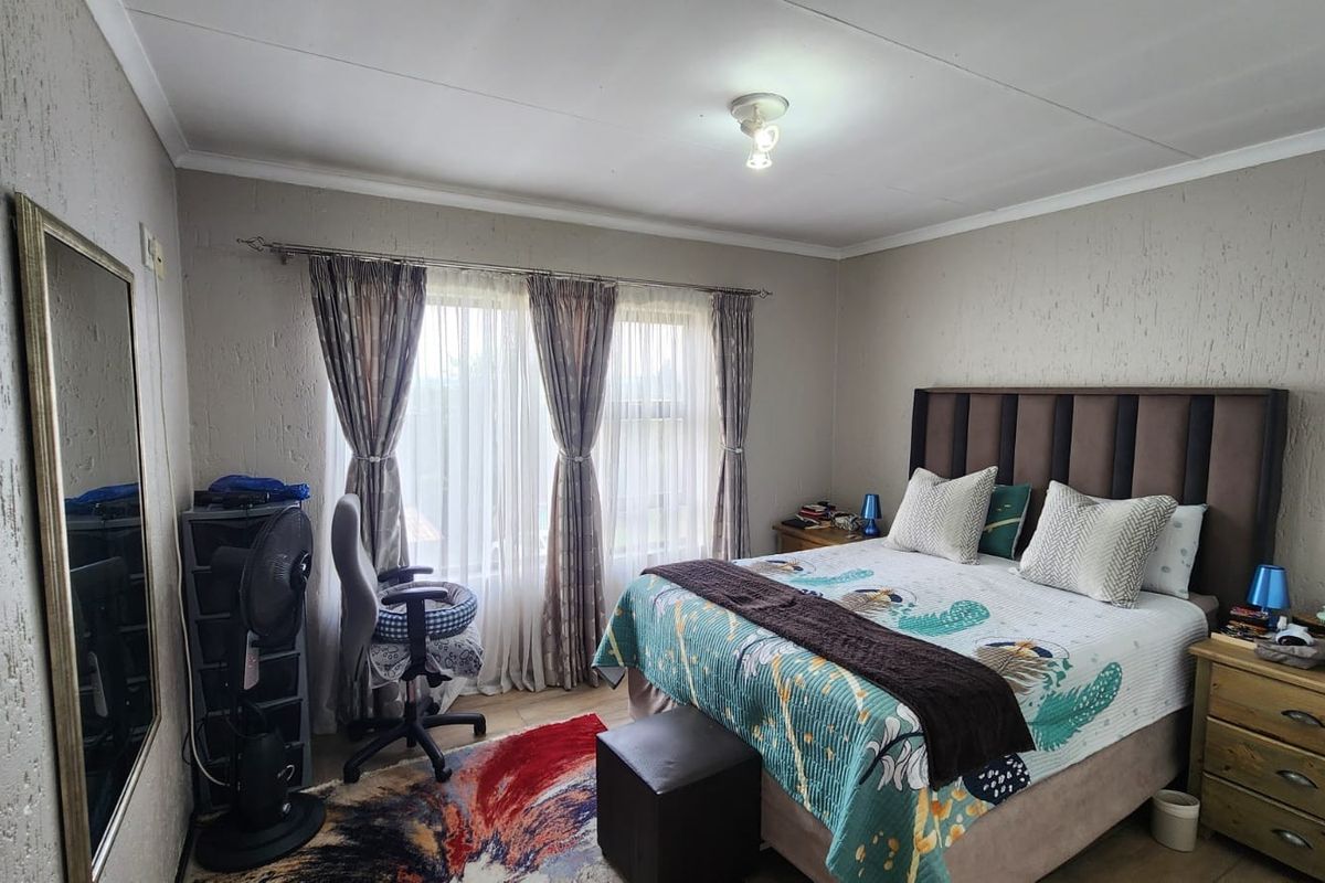 A bedroom featuring textured walls, a large window with curtain tracks, and a central ceiling light fixture.