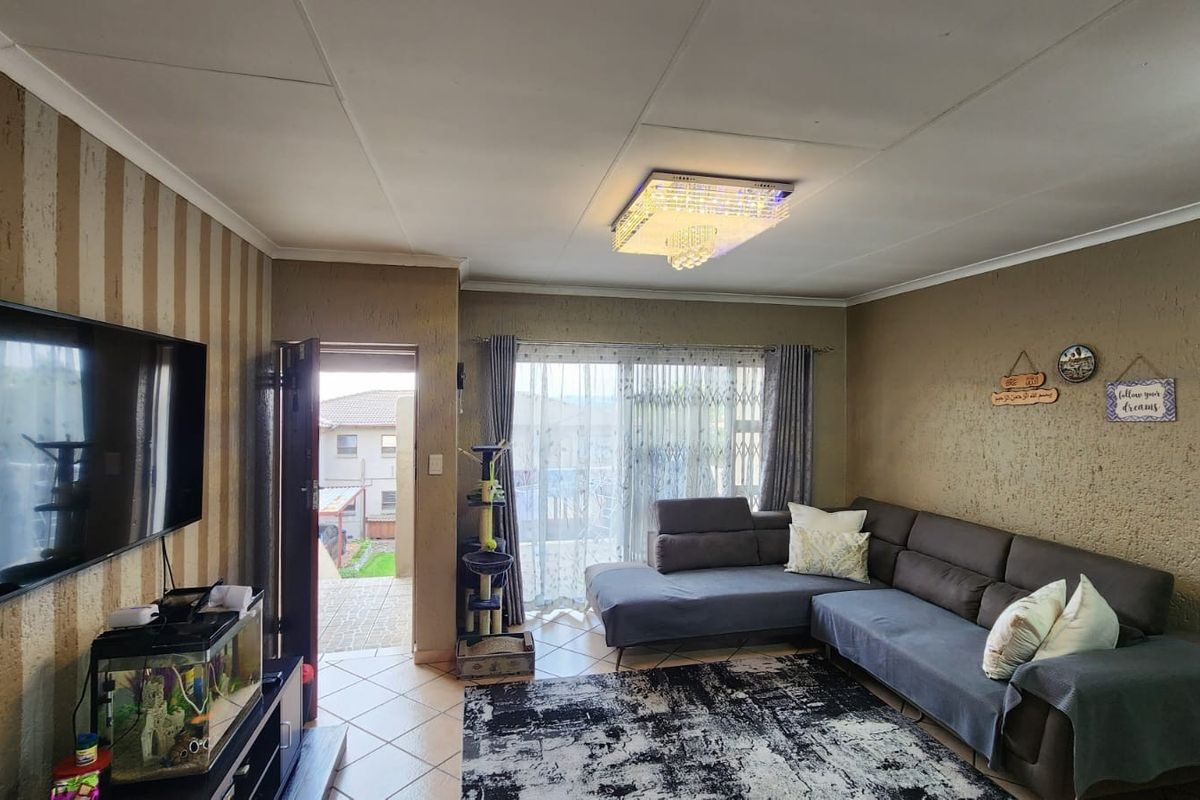 A comfortable living room featuring tiled flooring, a modern crystal ceiling light, and sliding glass doors providing access to an outdoor patio area.