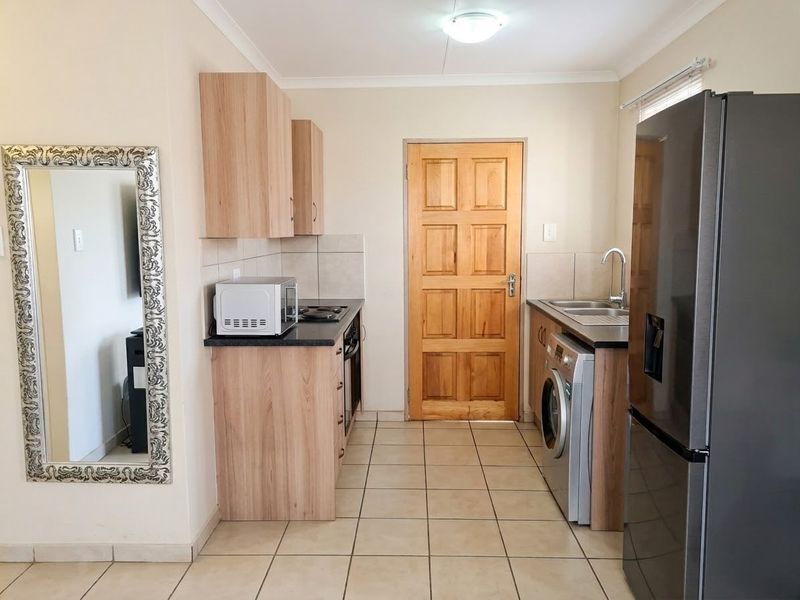A functional kitchen featuring light wood-tone cabinetry, dark countertops, tiled flooring, and integrated appliance spaces, providing a clean and practical culinary area.