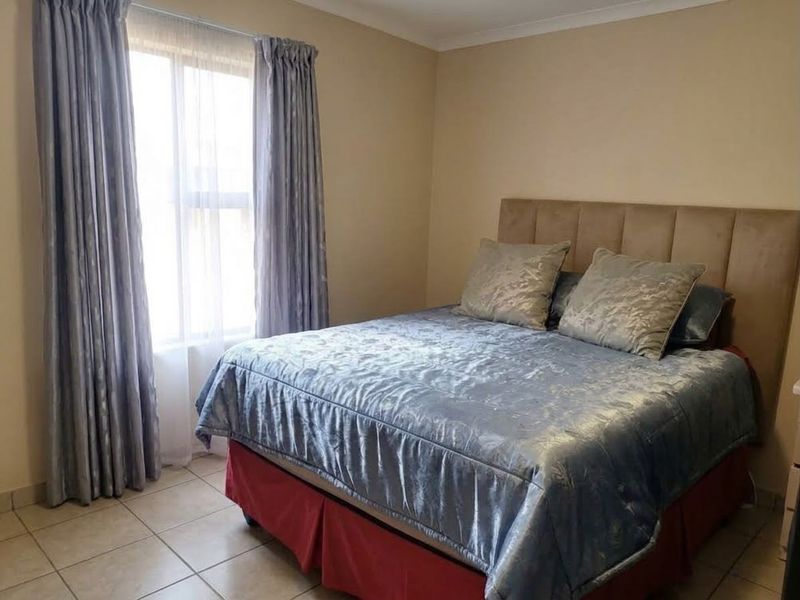 A functional bedroom featuring tiled flooring and neutral wall finishes, providing a comfortable and well-maintained living space.