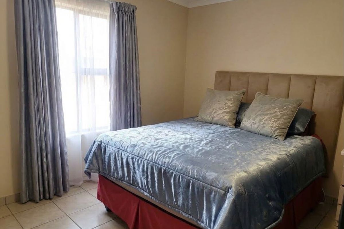 A functional bedroom featuring tiled flooring and neutral wall finishes, providing a comfortable and well-maintained living space.