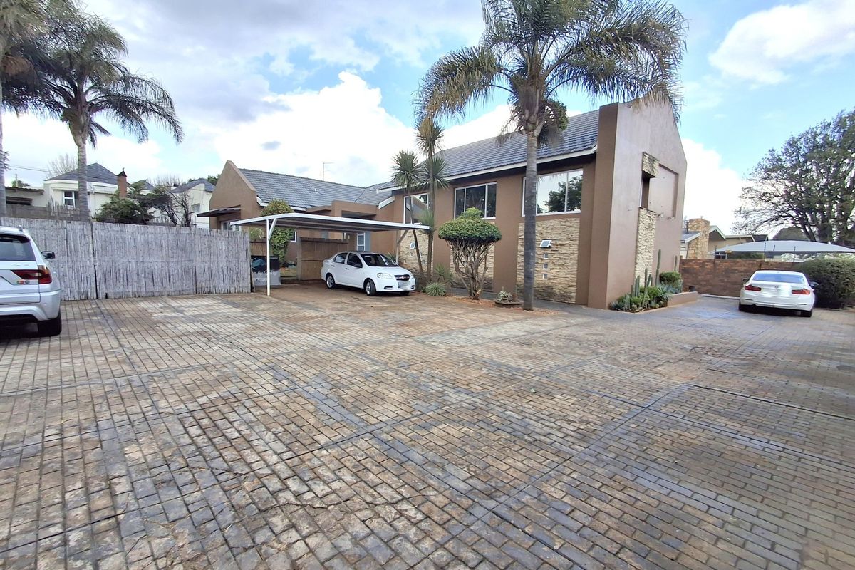 Front exterior view of the office property featuring a large paved driveway, carport, and stone-clad facade.
