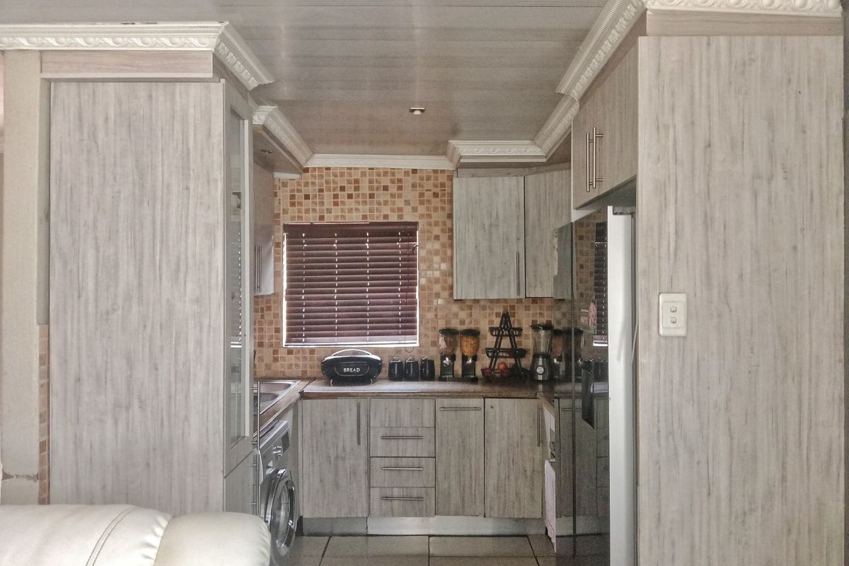 Compact kitchen featuring wood-look cabinetry, tiled backsplash, and integrated appliance space, offering a functional layout for efficient meal preparation.
