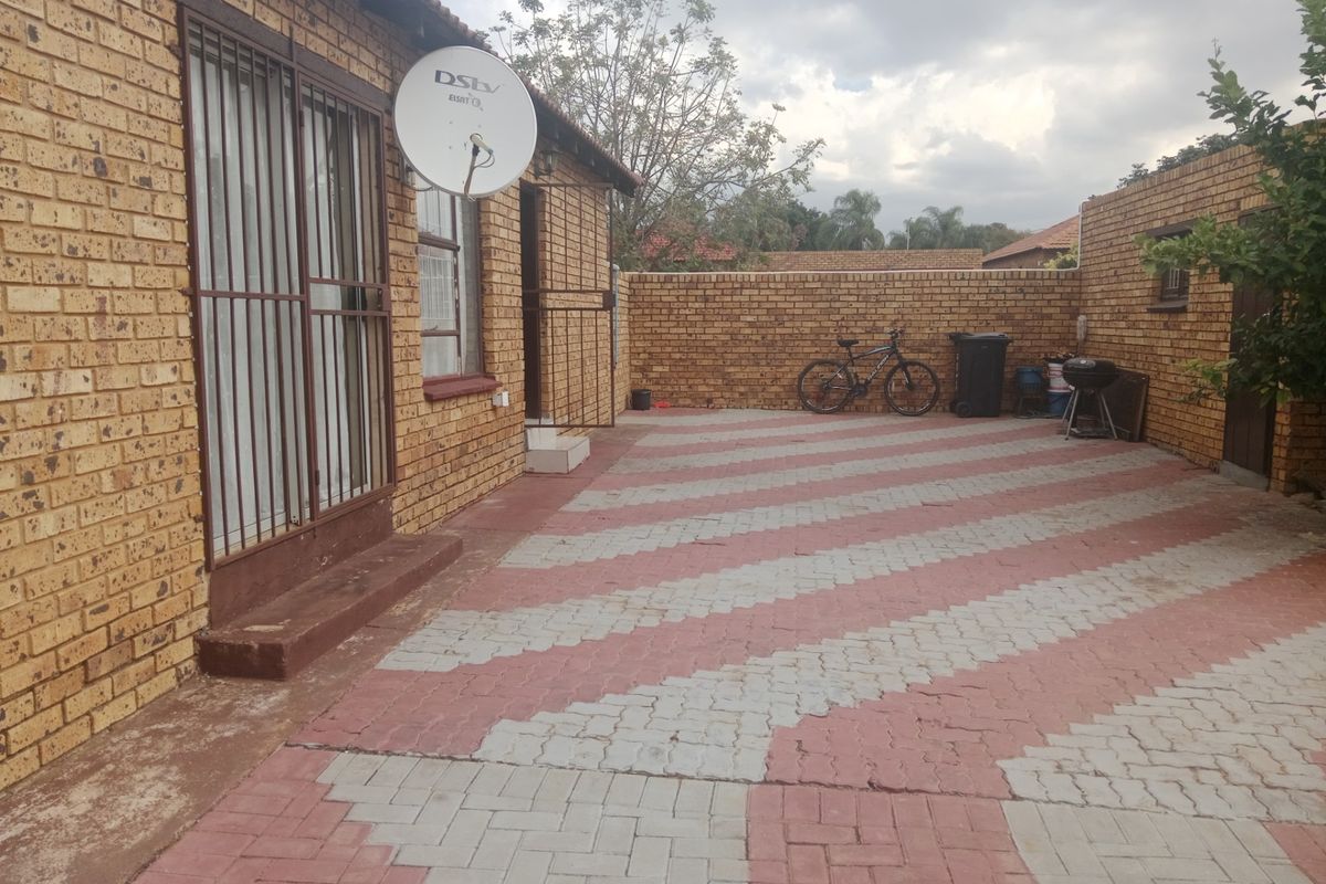A paved rear courtyard area featuring face-brick exterior walls, security gates, and a satellite dish installation.